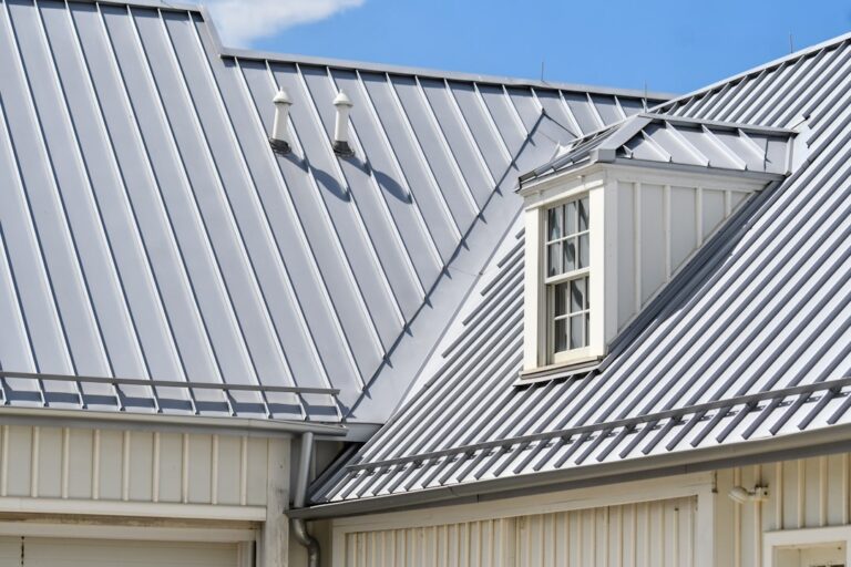 Grey metal roof, white siding, and a dormer window.